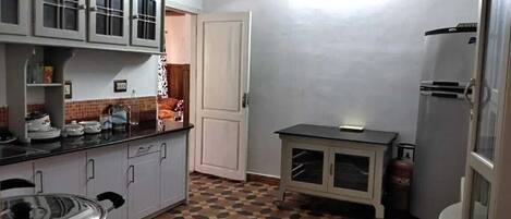 Eine kleine Küche mit Schränken, einer Arbeitsplatte, einem Tisch und einem Kühlschrank.