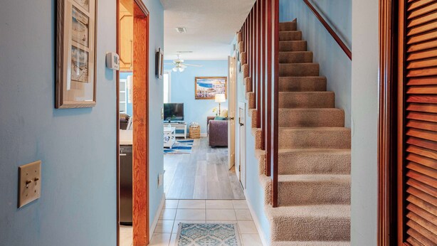 Un pasillo que conduce a una escalera con barandilla de madera y pared azul.