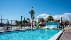 Piscina con zona delimitada por vallas, sillas de descanso y un pequeño edificio.
