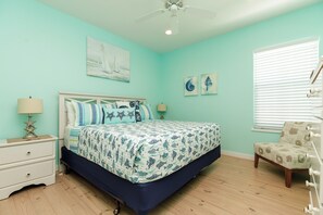 Une chambre à coucher avec un lit, des tables de chevet, une chaise et un ventilateur de plafond.