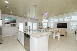 Een moderne keuken met een centraal eiland, witte kasten en hanglampen.