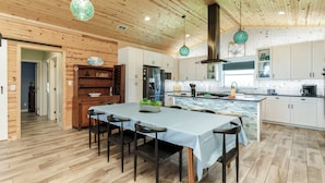 Une cuisine moderne aux murs en bois, dotée d’un îlot central et équipée d’une cuisinière, d’un évier et d’un grand plan de travail.