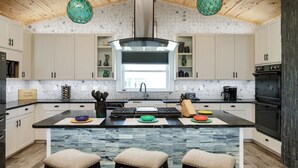 Une cuisine moderne dotée d’un îlot central, d’un plafond en bois et de luminaires suspendus.