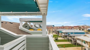 Ein Balkon mit Blick auf ein Wohngebiet, mit überdachtem Gang und Poolbereich.