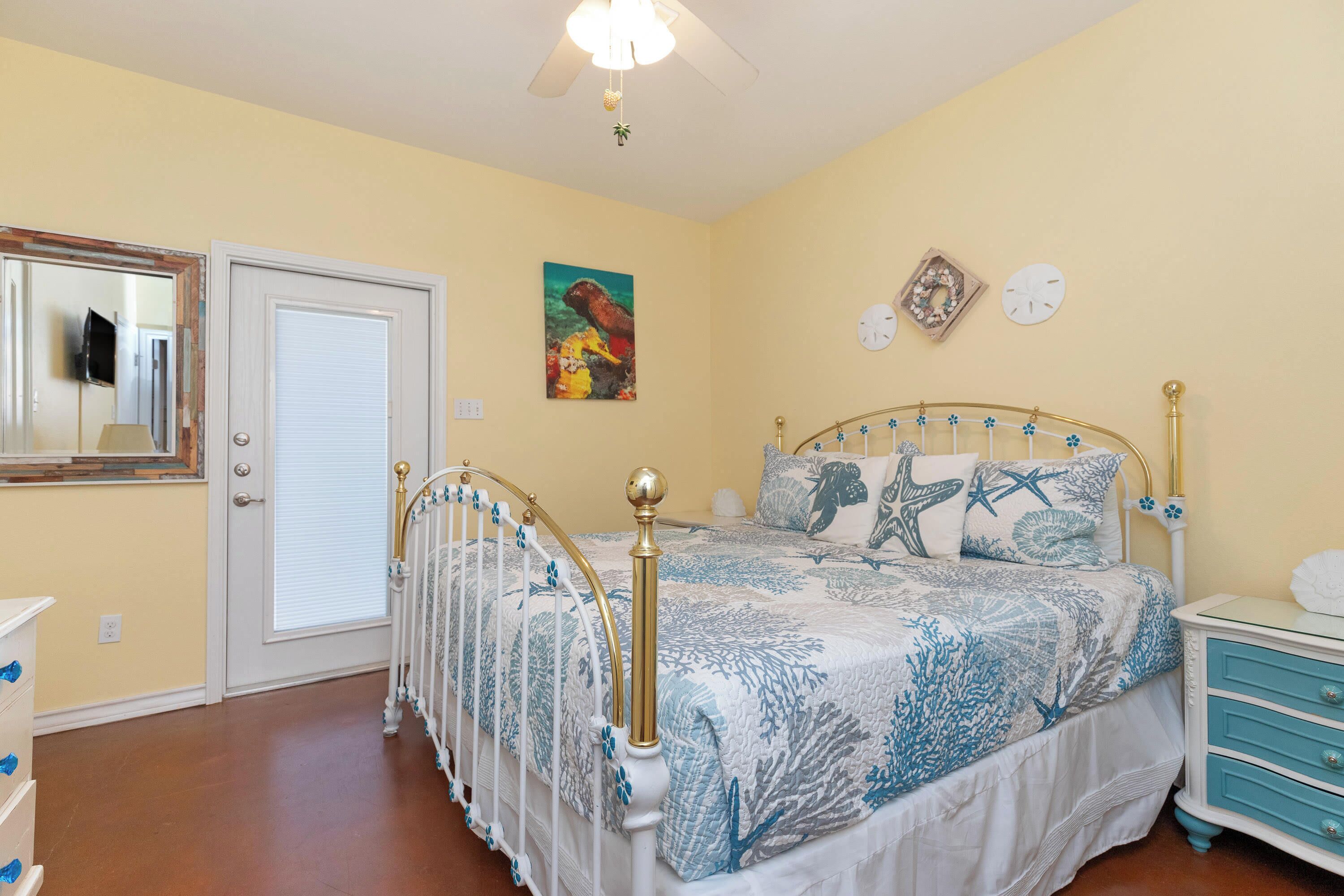 Une chambre à coucher avec un lit, une table de chevet, une commode, un miroir et un tableau accroché au mur.