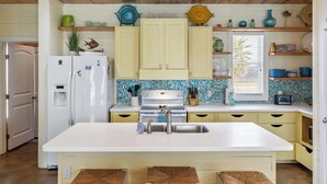 A kitchen with a central island, white cabinets, and a tiled backsplash. - Prime Location 5 Bedrooms | Pool | Sleeps 12 (Port Aransas)