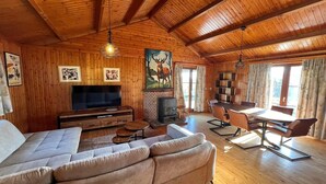 A spacious living room with a large sofa, a flat-screen TV, a fireplace, and a dining area with chairs and a table.