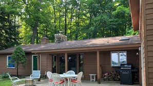 Une terrasse couverte avec une table et des chaises, un barbecue et une cheminée en pierre.