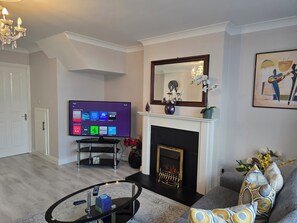 Ein Wohnzimmer mit Flachbildfernseher, Kamin, Sofa und einer Deckenleuchte.