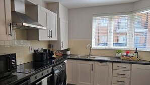 Een moderne keuken met een inbouw wasmachine, een spoelbak en een raam met zonwering.