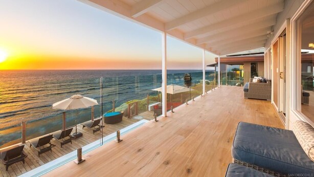 A spacious balcony with a wooden floor, overlooking a body of water during sunset. - Oceanfront Luxury with Pool/Spa, Beach Access (Encinitas)