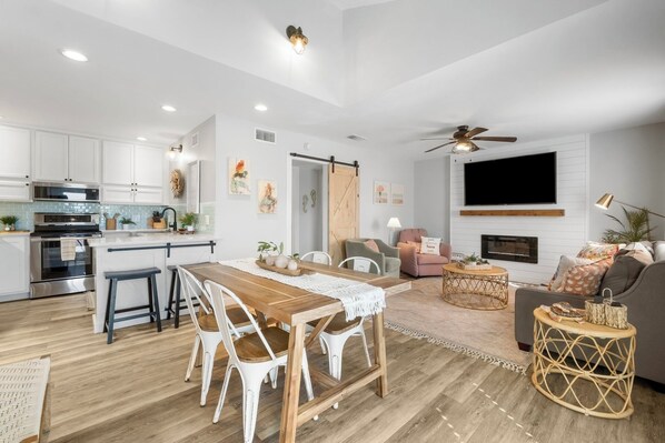 A modern kitchen with white cabinets, a wooden dining table, and a ceiling fan. - Coral Cabana - Steps to Beach - Beach Chair Service - Pool - Sea Cabins (Miramar Beach)