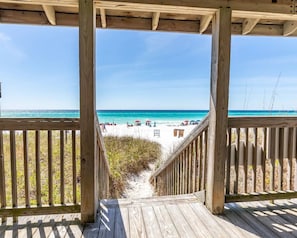 A wooden deck leading to a beach with clear turquoise water and a sandy shore. - Coral Cabana - Steps to Beach - Beach Chair Service - Pool - Sea Cabins (Miramar Beach)