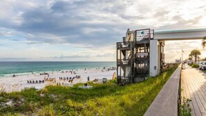 A beachside bar with a view of the ocean and beachgoers.