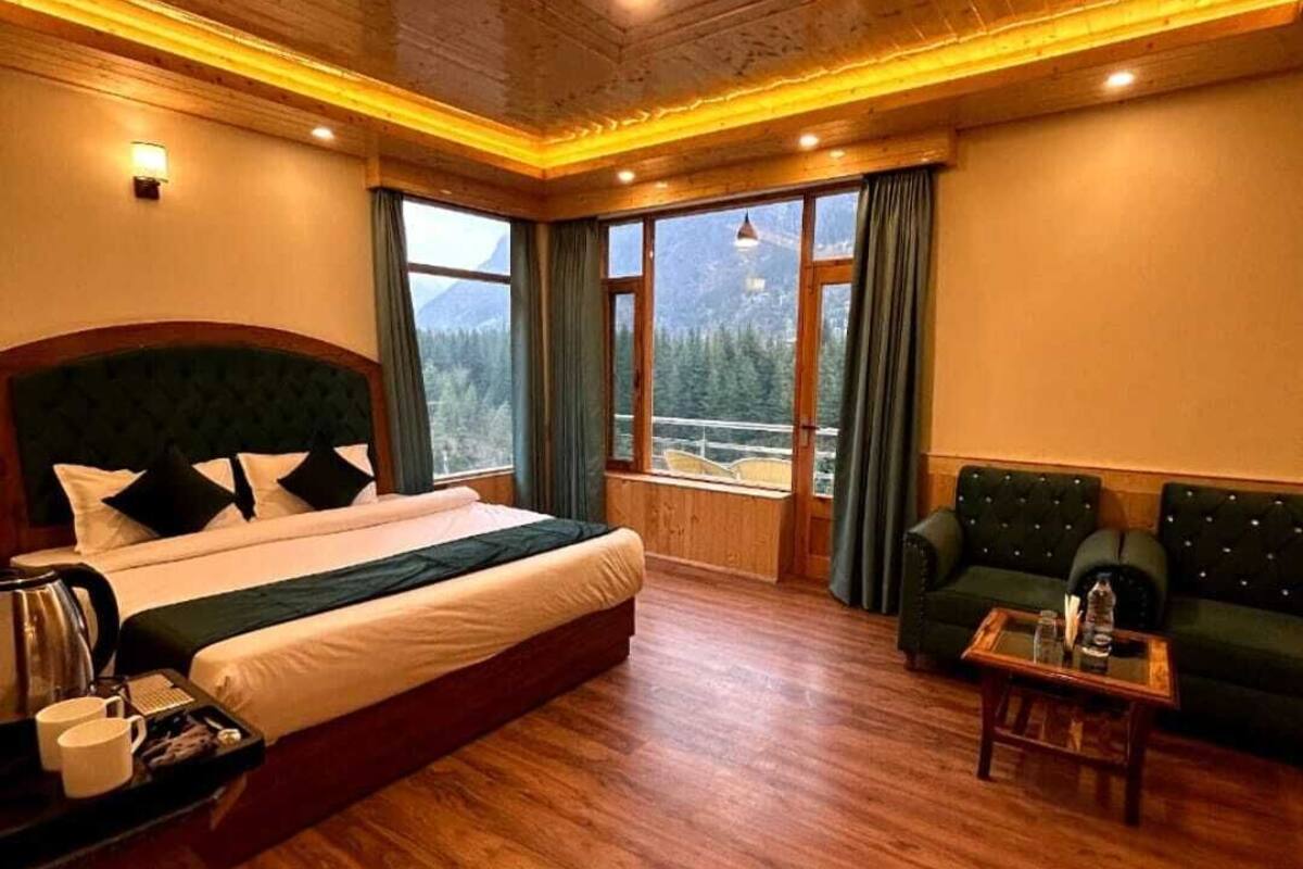 Dormitorio con piso de madera, una cama, un sofá y una ventana con vistas a la montaña.