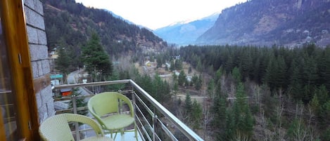 A balcony with wicker chairs overlooking a mountainous landscape.
