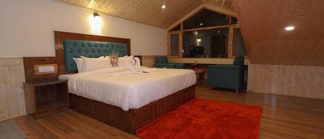 A bedroom with a wooden ceiling, a large bed, a red rug, and a window.