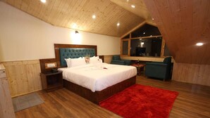 Una camera da letto con soffitto in legno, un letto grande, un tappeto rosso e vista sull'esterno.