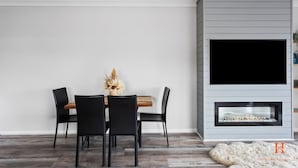 A dining area with a table and chairs, a fireplace, and a television mounted on the wall. - Stunning Ocean Views San Remo (San Remo)