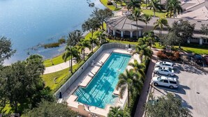 Luchtbeeld van een resort met een zwembad, palmbomen en een waterpartij.