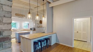 Une cuisine spacieuse dotée d’un îlot central, de luminaires suspendus et d’une enseigne indiquant « MAISON DE PLAGE ».