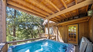 Eine Holzdiele mit Whirlpool, einer Terrasse und Blick auf Bäume.