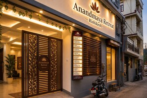 A building with a sign reading 'Anandmaya Retreat - Rishikesh' and a list of services including yoga, astrology, and treks. - Anandmaya Retreat Tapovan Rishikesh (Rishikesh)