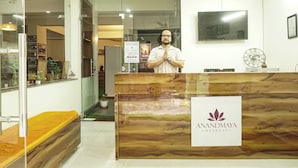 A reception desk with a wooden finish and a sign for Anandmaya Retreat. - Anandmaya Retreat Tapovan Rishikesh (Rishikesh)