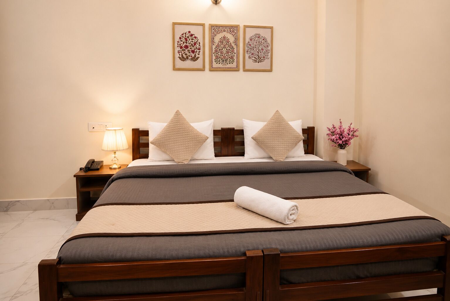 A hotel room with a bed, bedside tables, a lamp, and wall art.