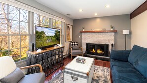 Una sala de estar con chimenea, televisor y sofá.