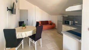 Una cuina compacta amb microones, un refrigerador petit i zona de menjador amb taula i cadires.