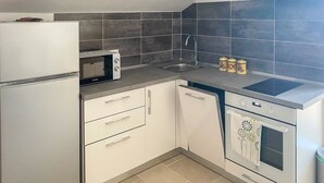 Cuina compacta amb nevera, microones, rentatge, rentavaixelles i forn.