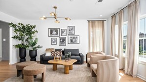 A modern living room with a sofa, ottomans, a coffee table, and a large plant.