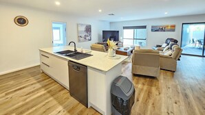 A modern kitchen with a dishwasher, a sink, and a trash bin. There is a dining area with a sofa and a coffee table. - Casa Del Batson - Your home away from home (Robe)