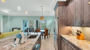 A modern kitchen with dark wood cabinets, a marble countertop, and stainless steel appliances.