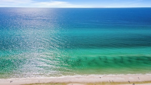 Une plage à l’eau turquoise et limpide, bordée d’un rivage sablonneux.
