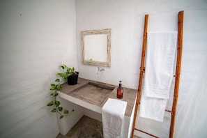 A bathroom with a wooden vanity, a mirror, a sink, a towel rack, and a potted plant.
