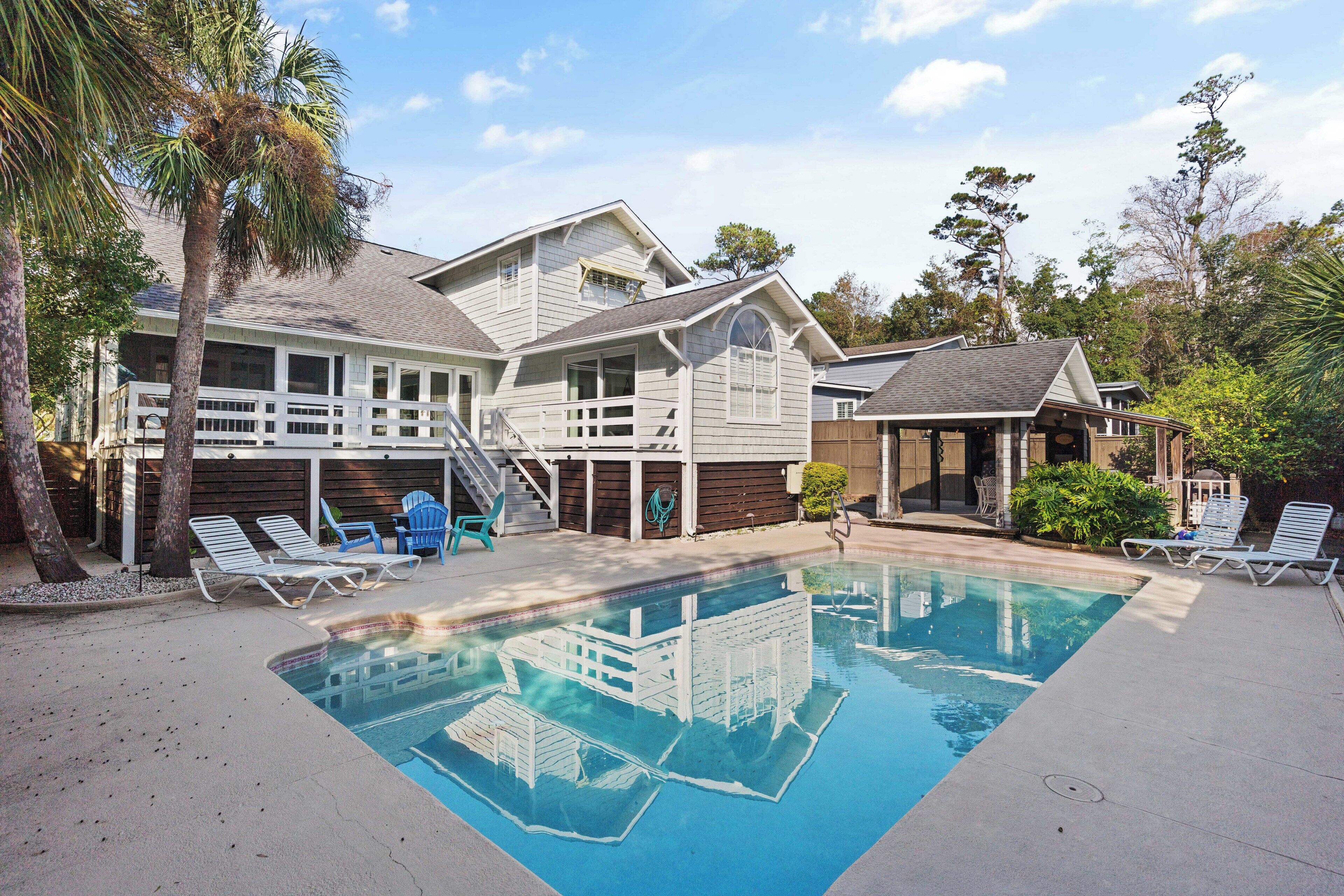 A house with a swimming pool, a covered patio, and a staircase leading to the upper level.
