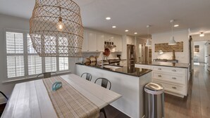Una cocina moderna con armarios blancos, una isla central y una lámpara colgante.