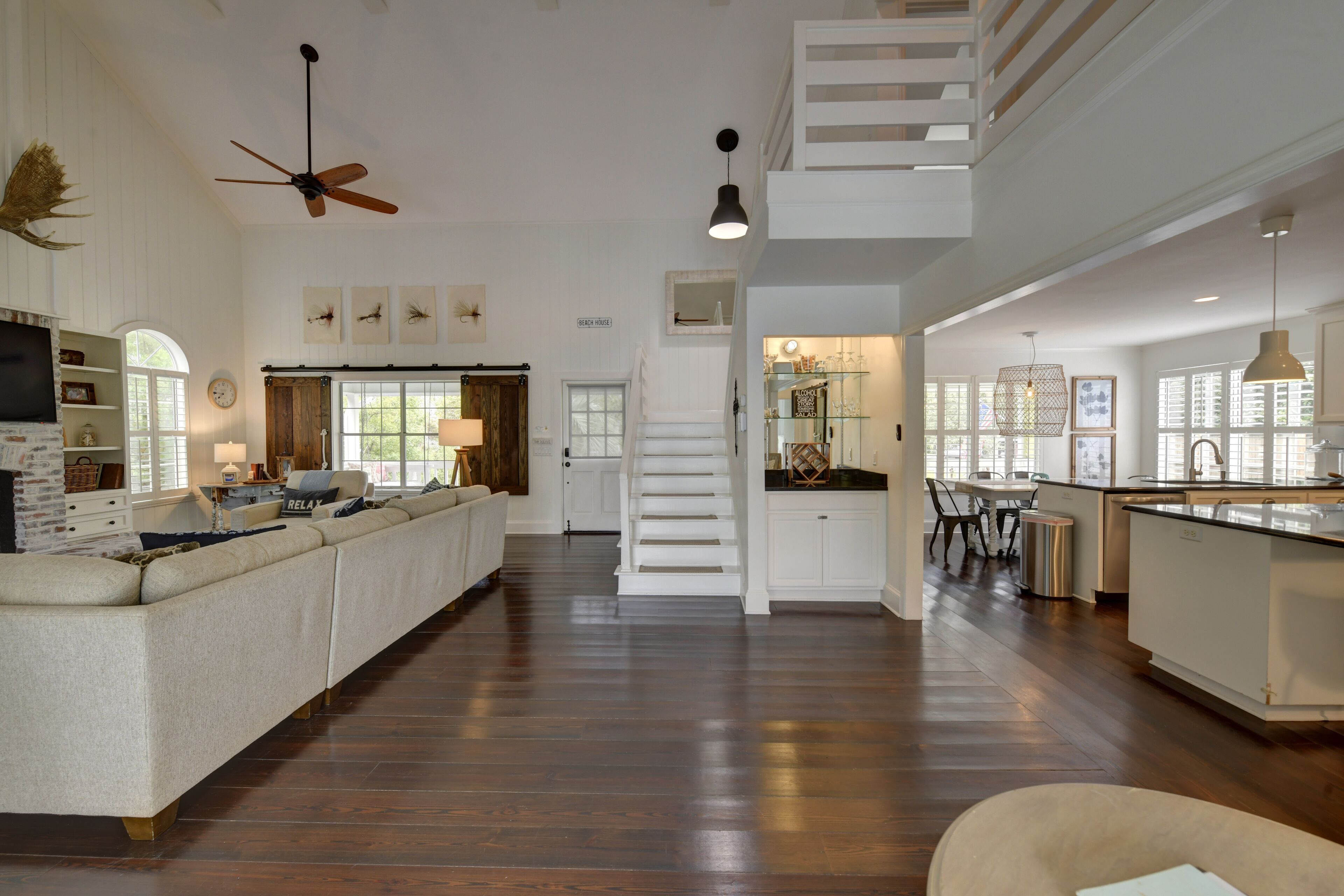 Amplia sala de estar con un sofá grande, una mesa de comedor y una cocina con una escalera.