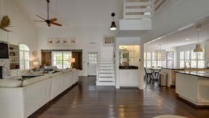 Amplia sala de estar con un sofá grande, una mesa de comedor y una cocina con una escalera.