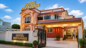 Ein Hotel mit einem Schild, auf dem 'HOTEL REST & PEACE' steht, einem verschlossenen Eingang und dem Schriftzug 'DHARMI NIWAS' am Gebäude.