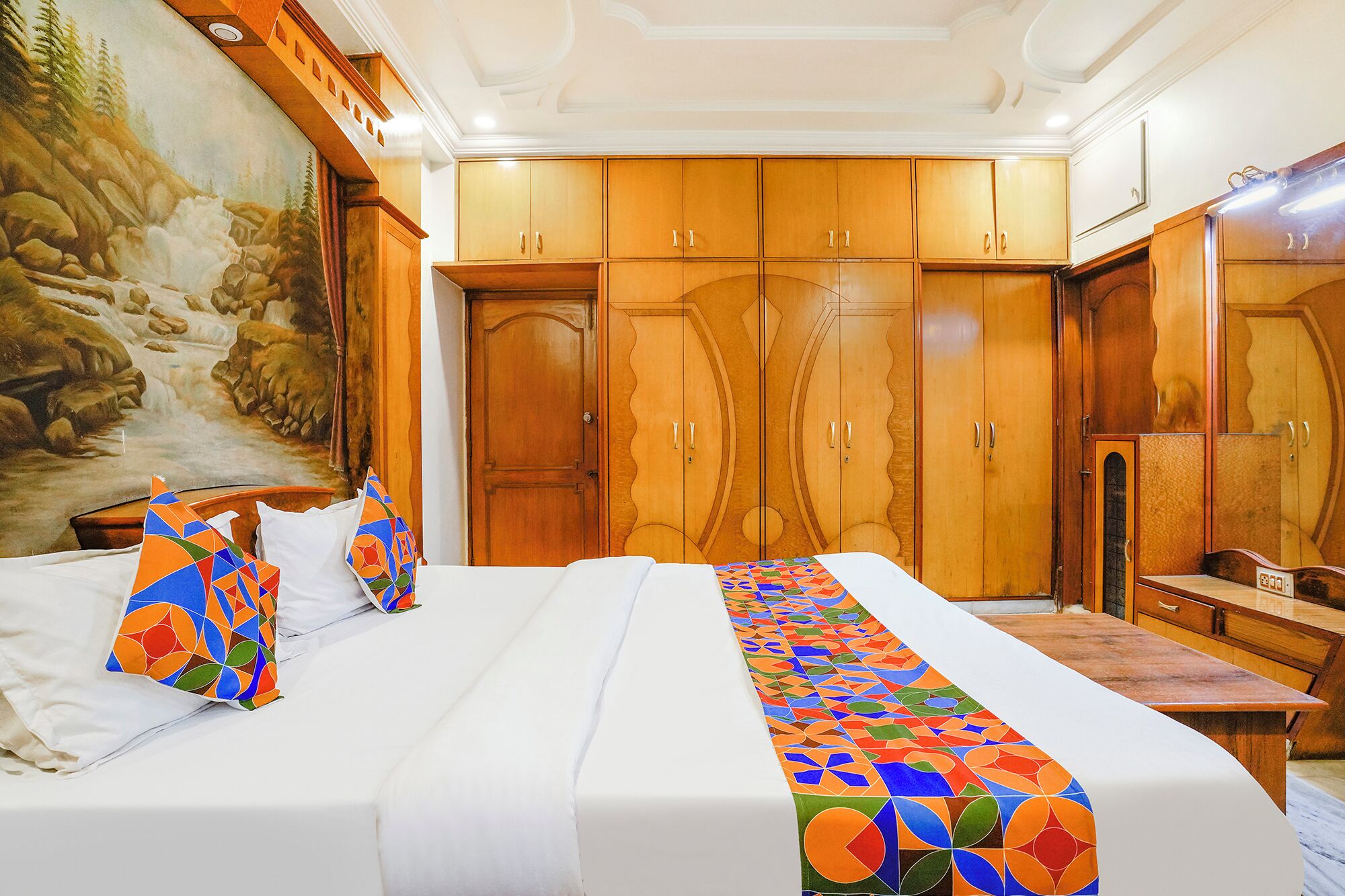 Une chambre d’hôtel avec un grand lit, une armoire en bois et un tableau accroché au mur.