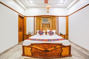 A bedroom with a wooden bed frame, a white mattress, and a colorful geometric-patterned bedspread.