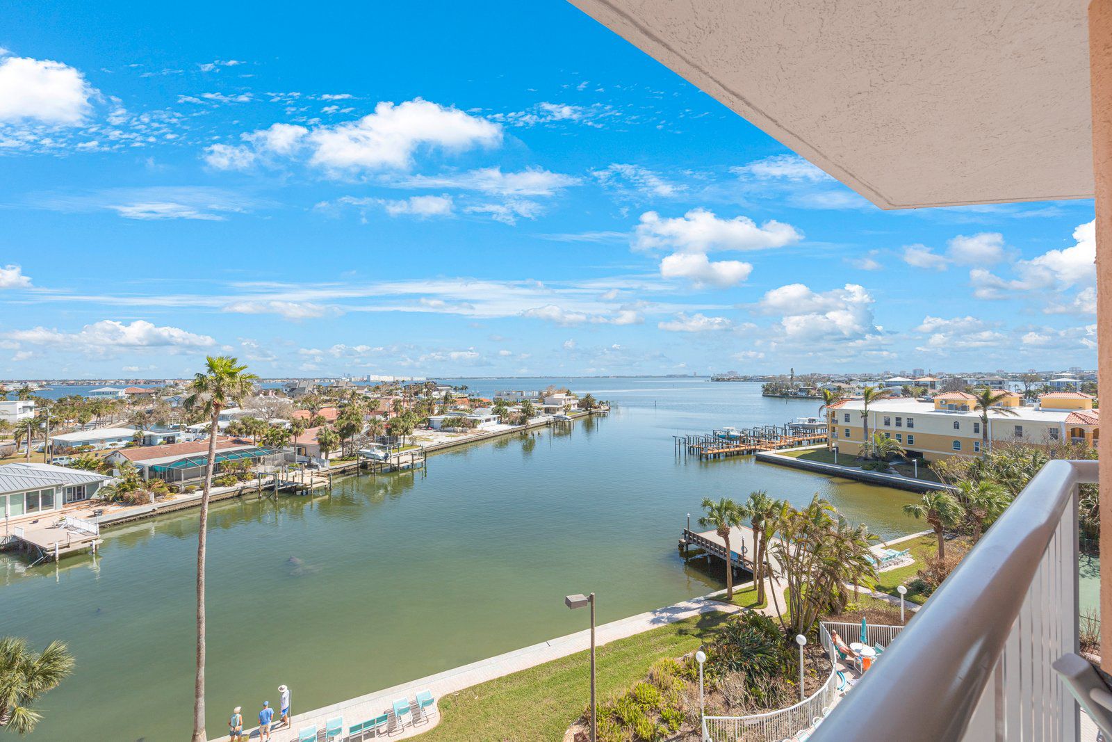 A waterfront view from a balcony overlooking a marina with boats, a dock, and residential buildings.