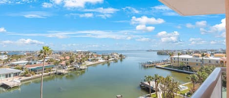 A waterfront view from a balcony overlooking a marina with boats, a dock, and residential buildings.