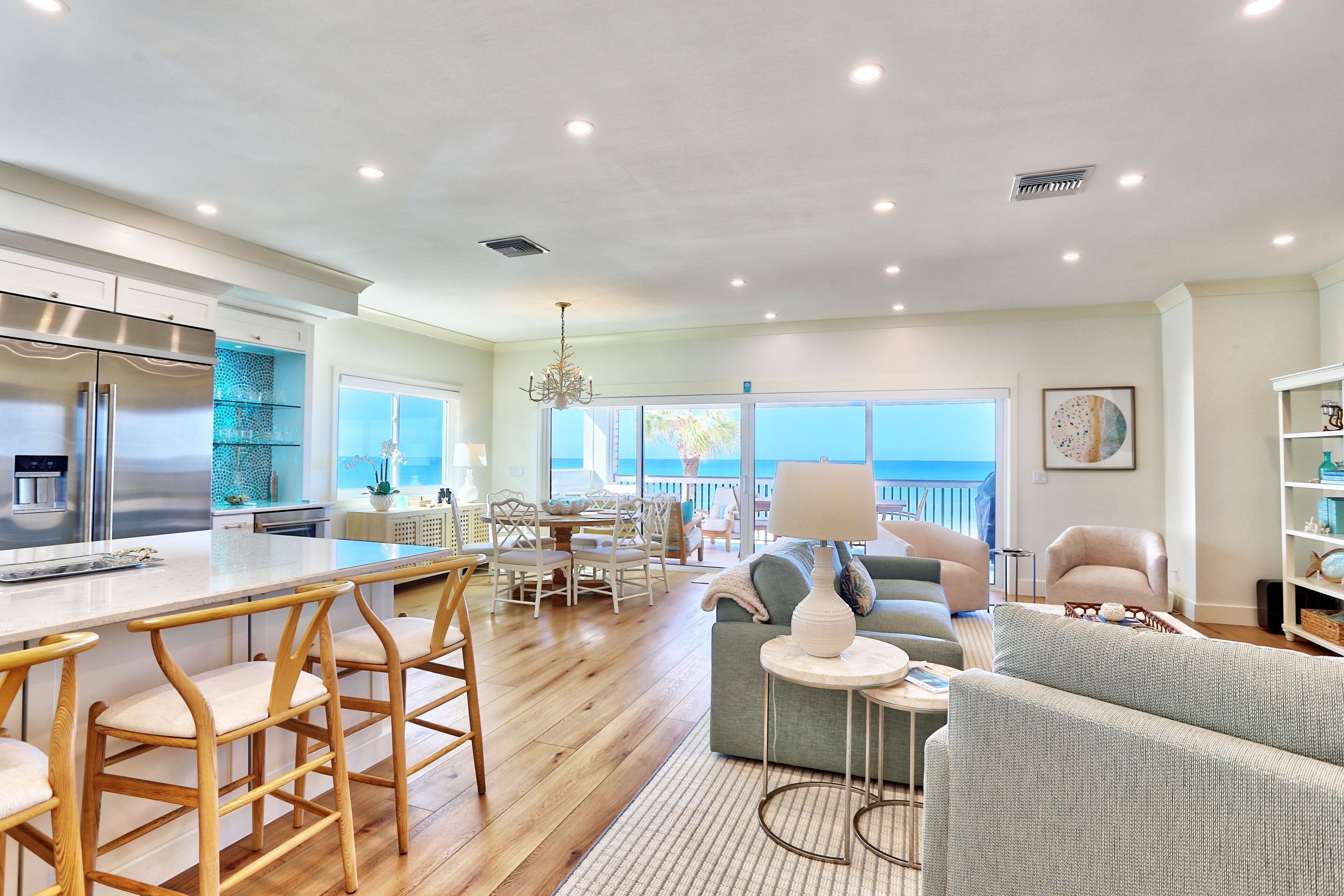 A spacious living area with a large kitchen, a dining area, and a view of the ocean.