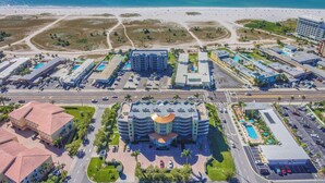 An aerial view of a coastal hotel with multiple buildings, a central structure with a curved roof, and a beach in the background. - ☀️Crystal Palms 405 - Excellent Location and Amenities☀️ (Treasure Island)