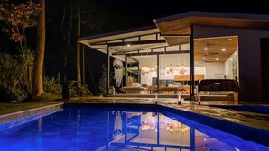 A modern house with a swimming pool, glass doors, and a dining area with chairs and tables. - Bungalow Heliconia I Tropical I Quiet I La Fortuna (Provinz Alajuela, San Carlos, Costa Rica)