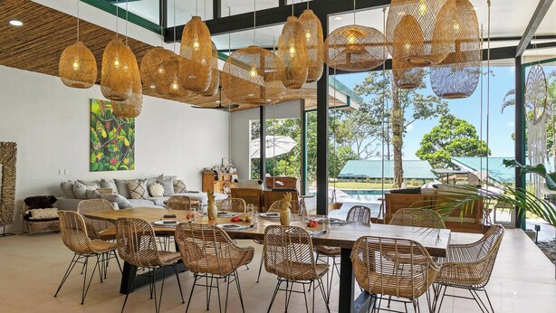 A spacious dining area with a large table and wicker chairs, a sofa, and a painting on the wall. - Bungalow Heliconia I Tropical I Quiet I La Fortuna (Provinz Alajuela, San Carlos, Costa Rica)